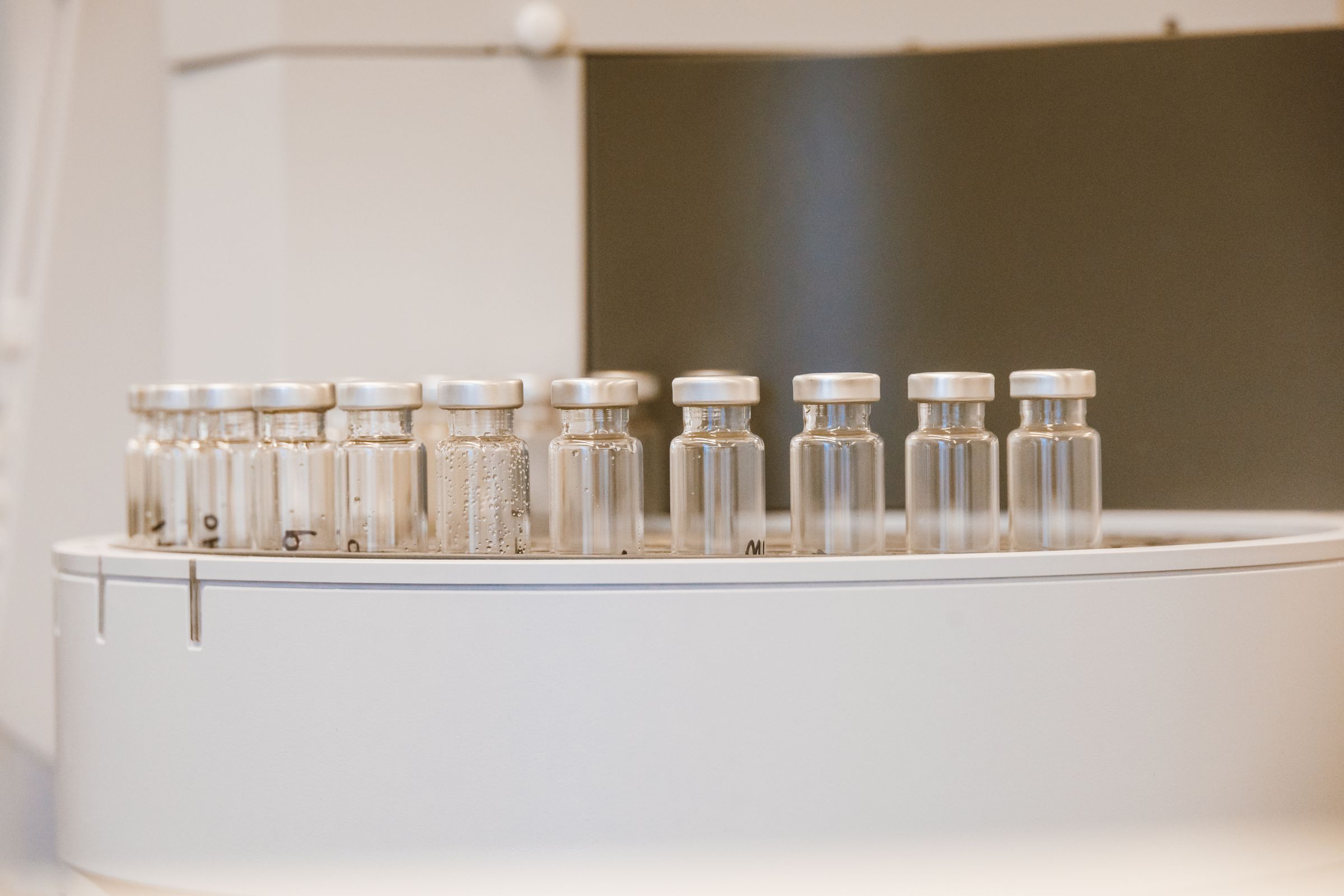 Sealed batch vials staged in a lab autosampler tray, each logged before release